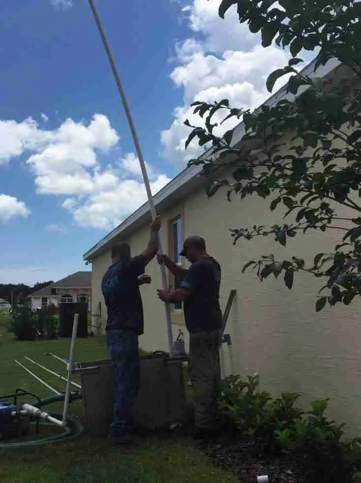 Two WaterCare crew members raising well pipe during a residential well installation